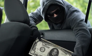 Stock photo of a thief stealing a $1000 Bill from a car.
